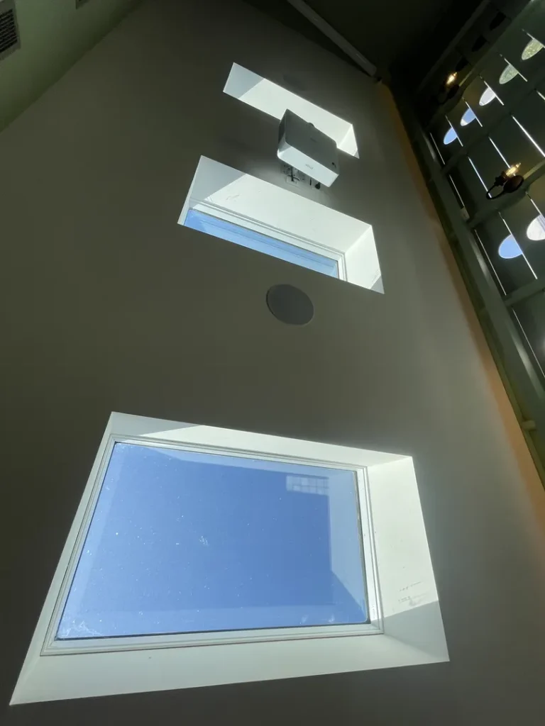 Modern interior lighting and window design in high ceiling room.