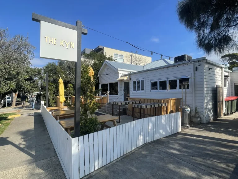 Outdoor dining area at "The Kyn" restaurant under clear sky.