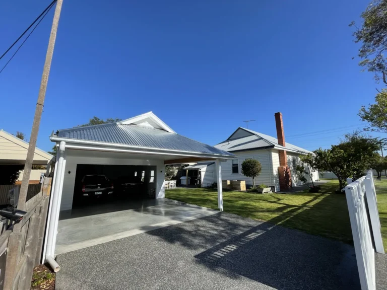 White suburban home with carport and chimney.