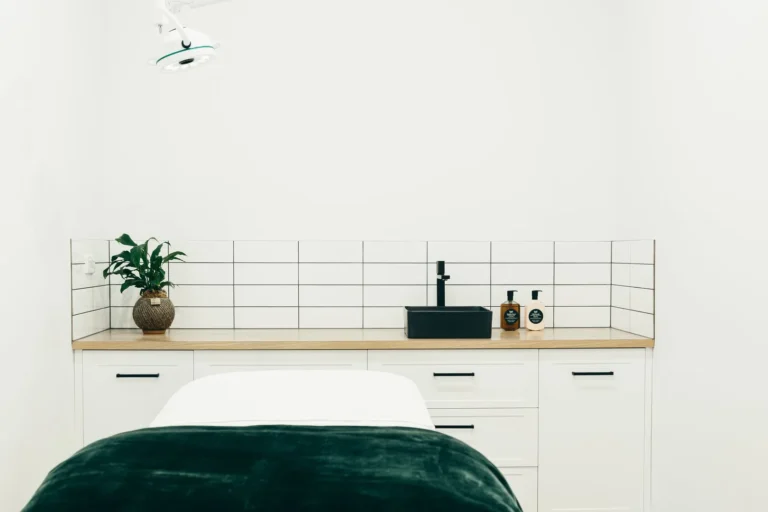 Modern minimalist bathroom with black faucet and green plant.